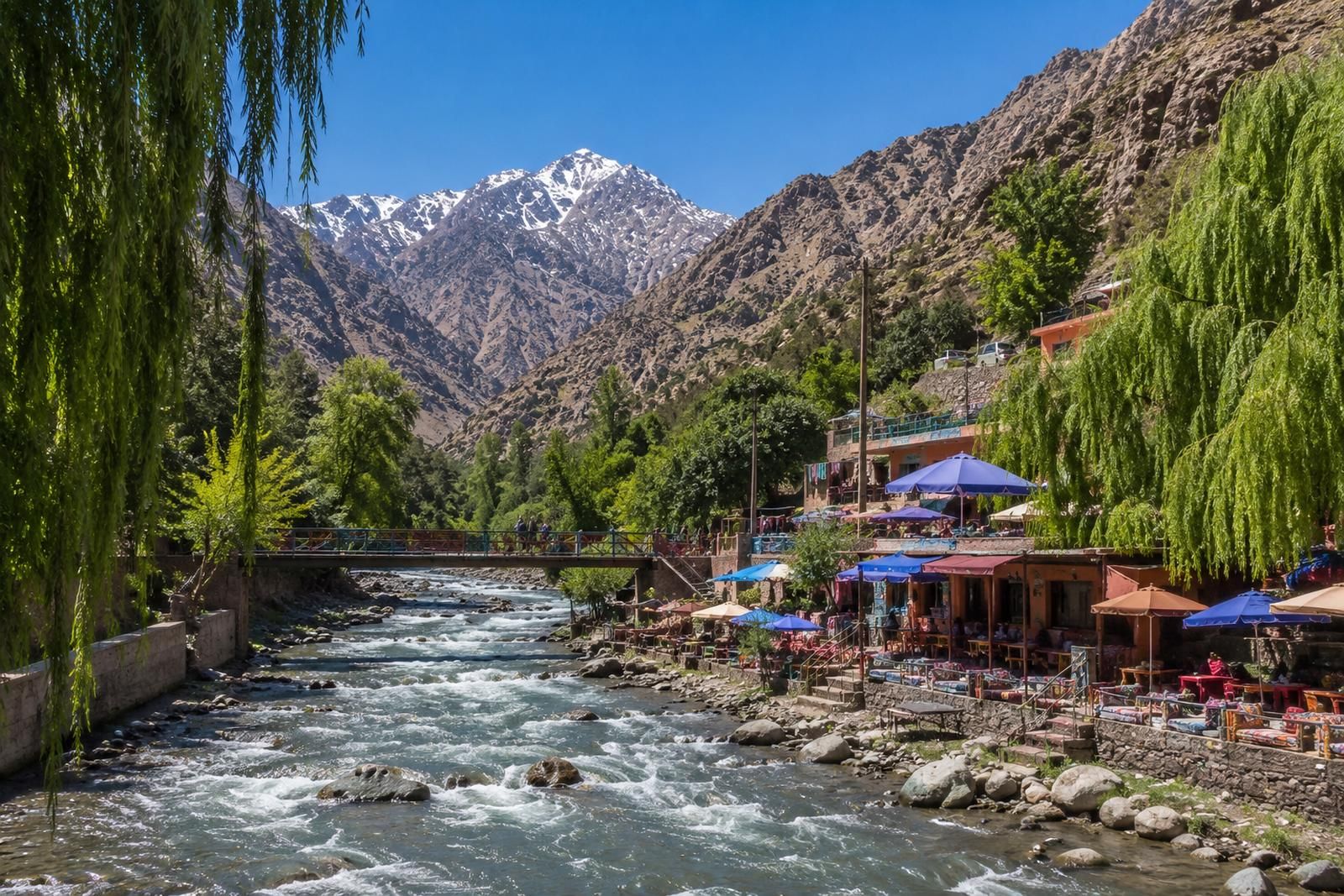 Riverside cafes under parasols in the Ourika valley, snow still on the High Atlas behind